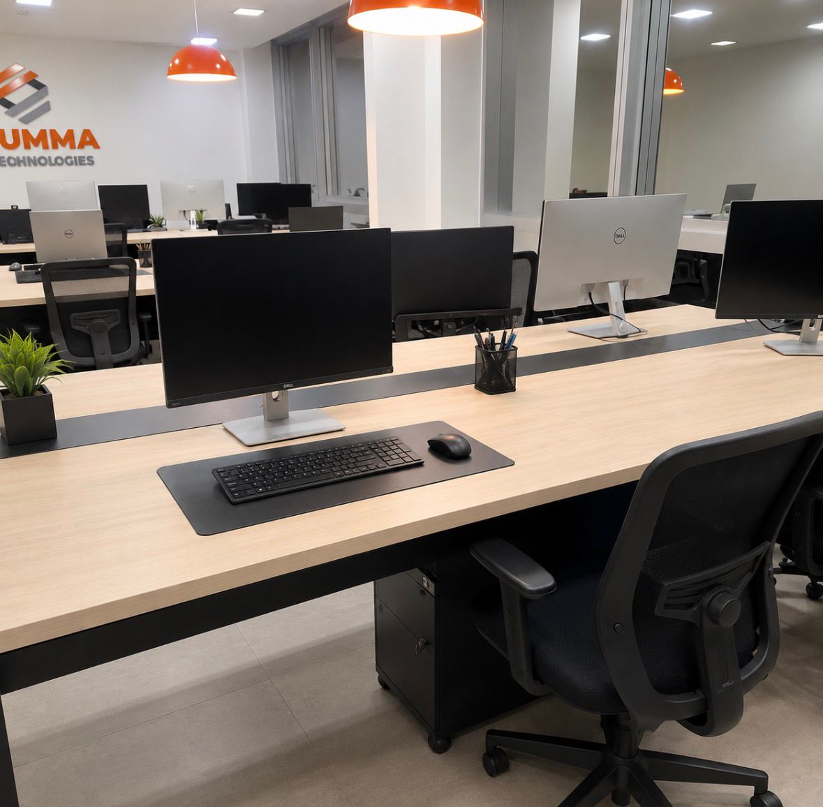 Escritório da Prumma Technologies com estações de trabalho e a marca na parede